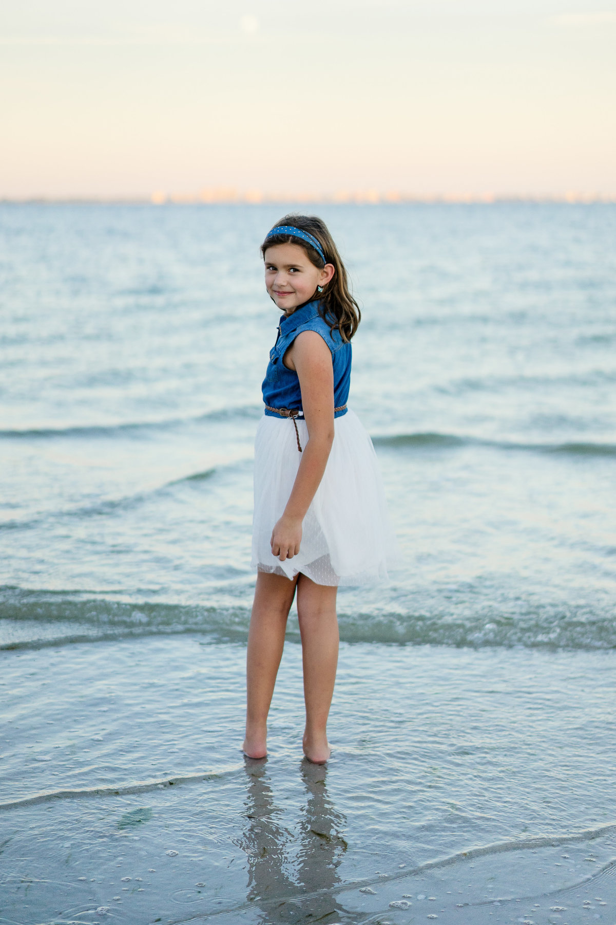 Young girl with feet in the water on Sanibel beach Florida