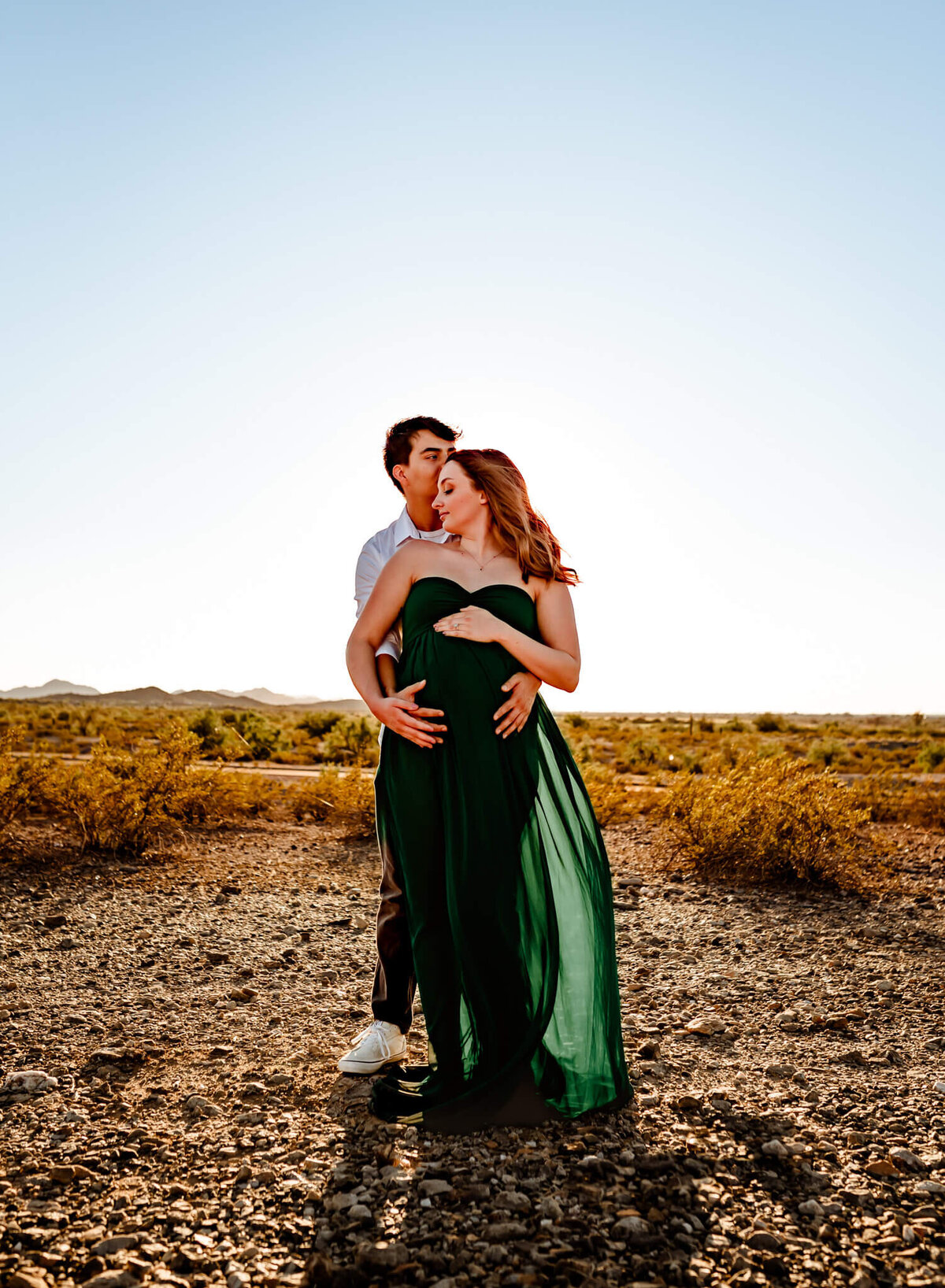 husband hugging wife and baby bump from behind during maternity session with Cactus & Pine Photography LLC in Arizona