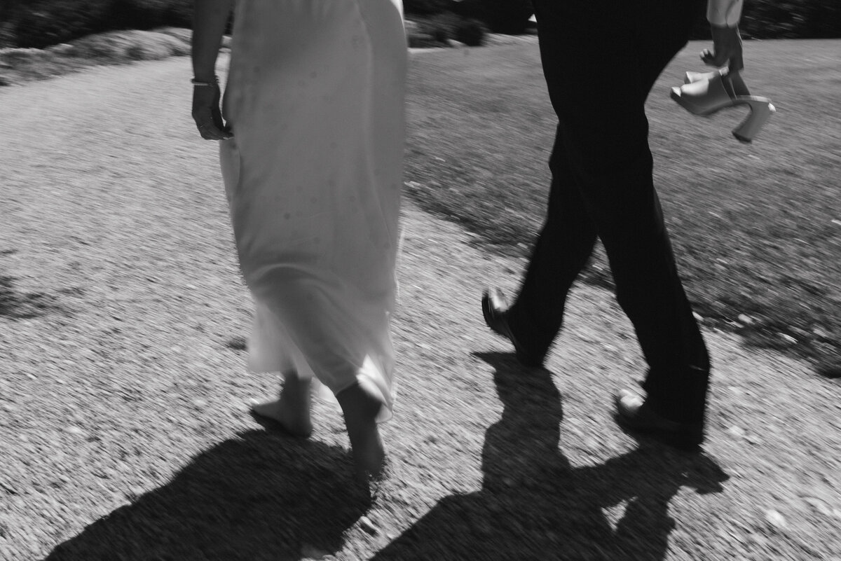 a black and white motion blur photo of a couple walking together on a gravel pathway. 
