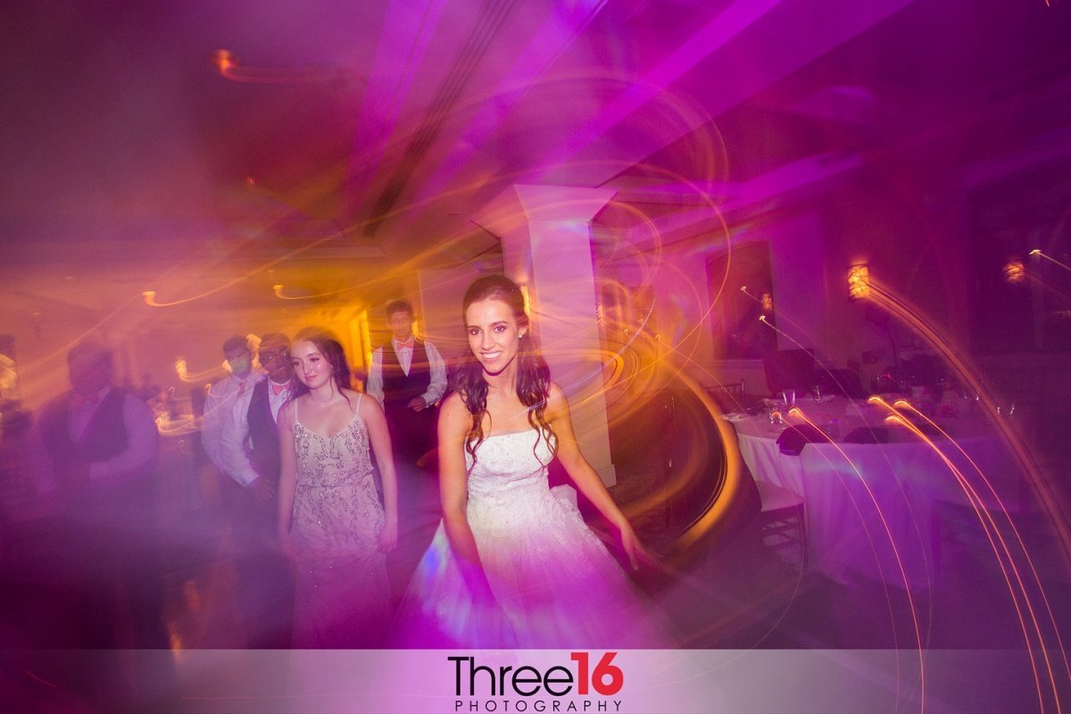 Bride dancing with her guests in red toned photo