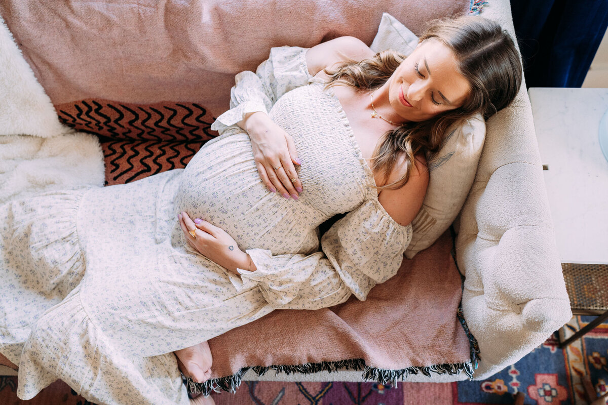 pregnant mother reclines on couch while cradling belly