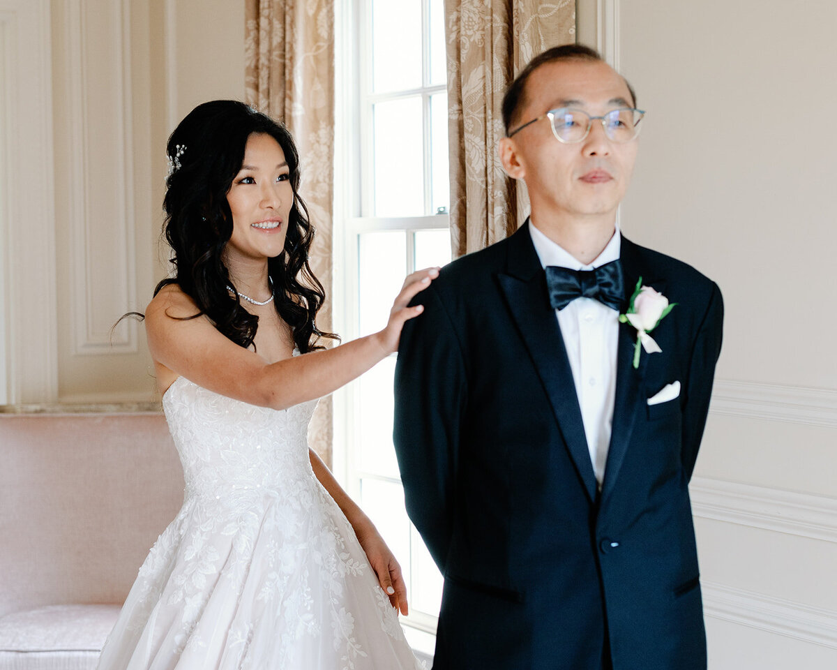Bride reaching towards Dads shoulder for their first look