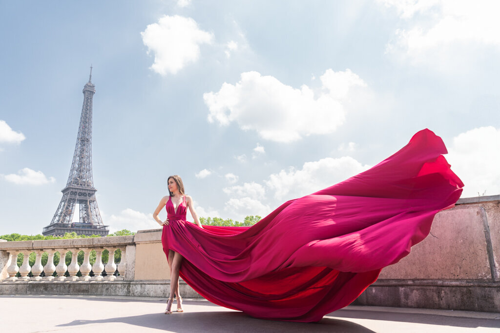 Flying dress portrait session at Mirabeau bridge with woman in pink flowing gown and Eiffel Tower backdrop