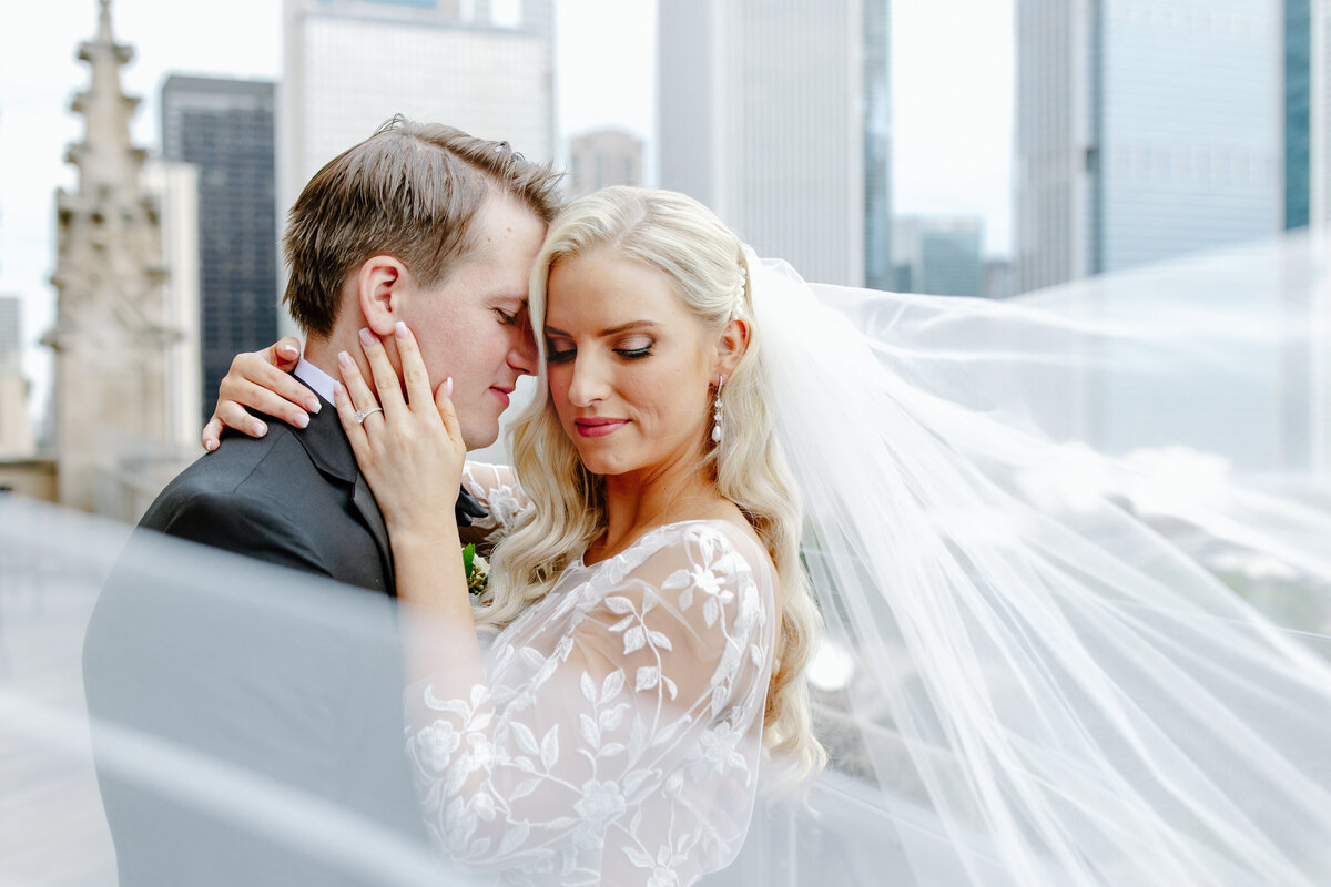 Bride and groom kiss surrounded by their wedding parties cheering