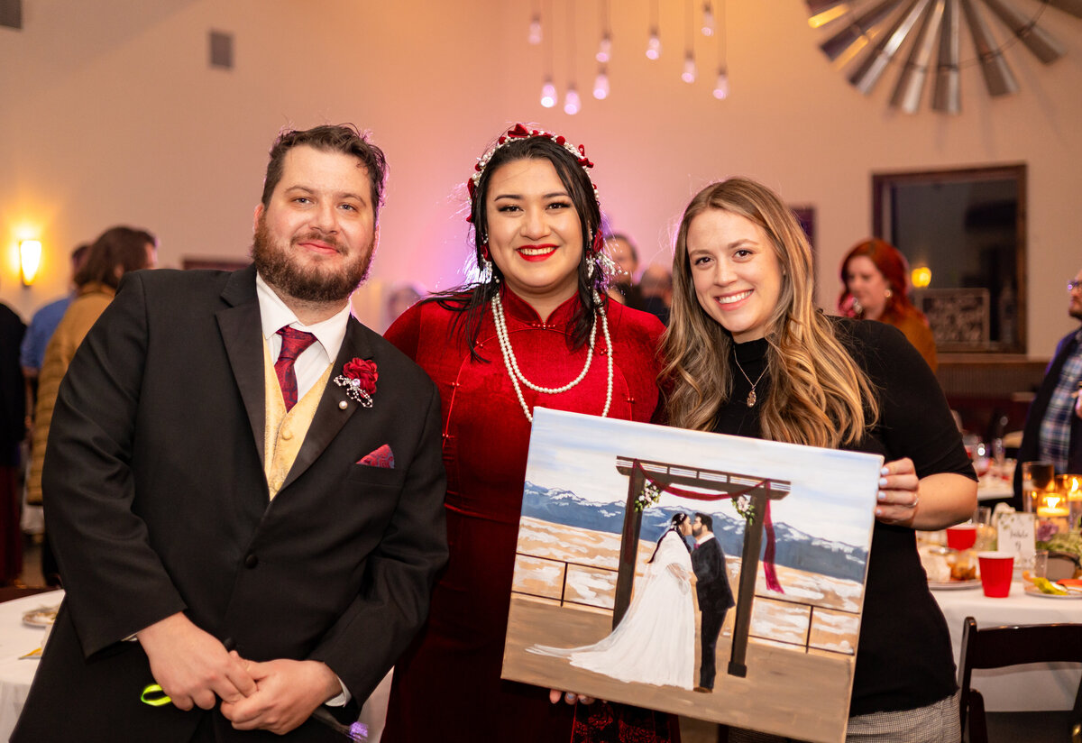 The live wedding artist, Olivia Andruss, poses with couple painted at their wedding at the end of the night