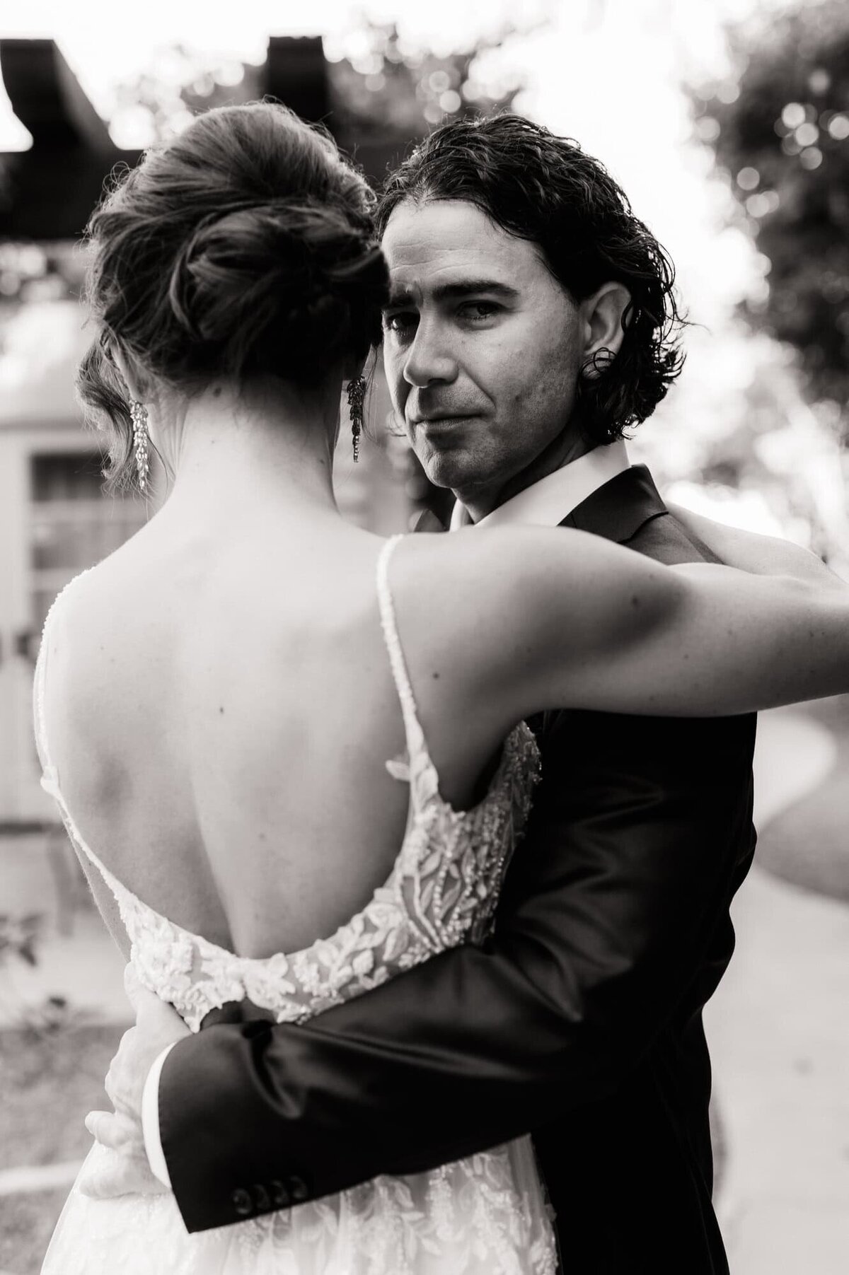 Groom looking back at the camera as he holds his bride close.