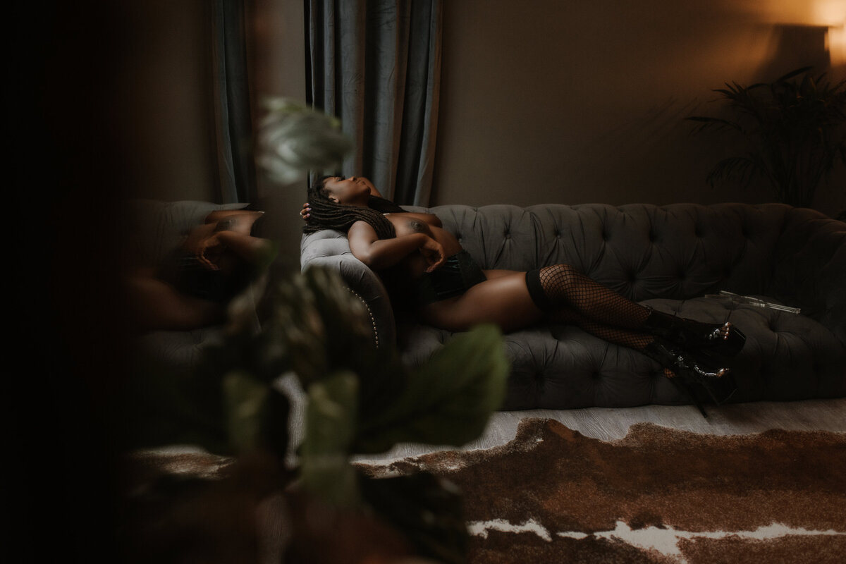 A nude woman poses while laying on a couch  in the Victoria, BC boudoir studio.