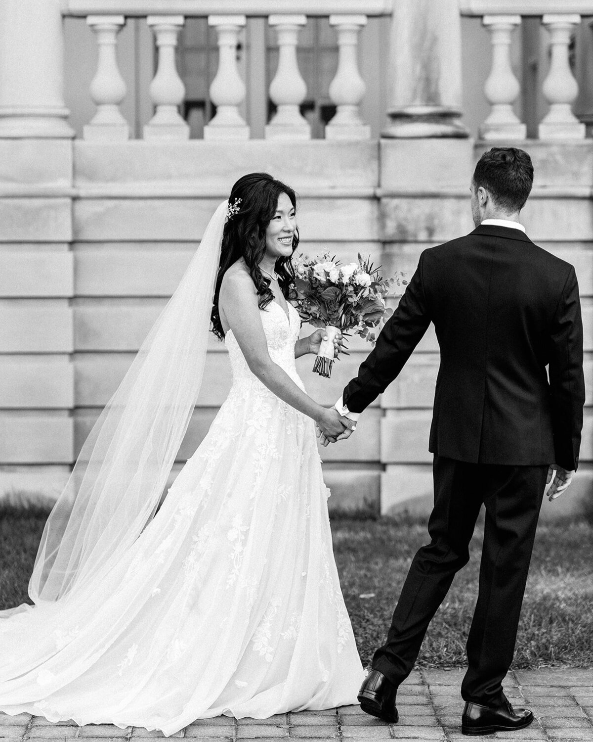 Bride and groom walking along as she holds her bouquet