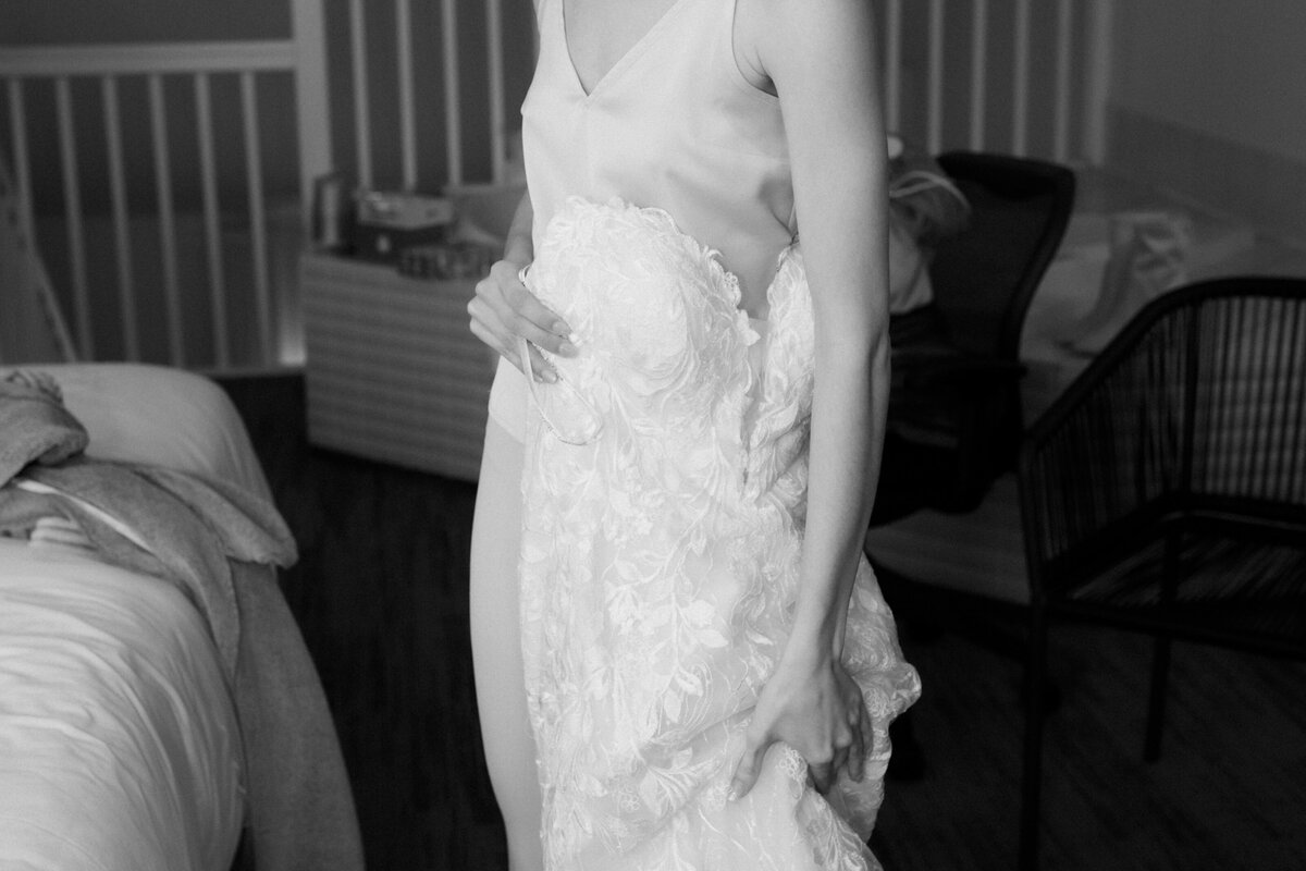 black and white portrait of a bride holding her dress by her side