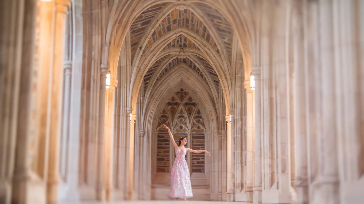 A girl with her arms up in a grand corridor