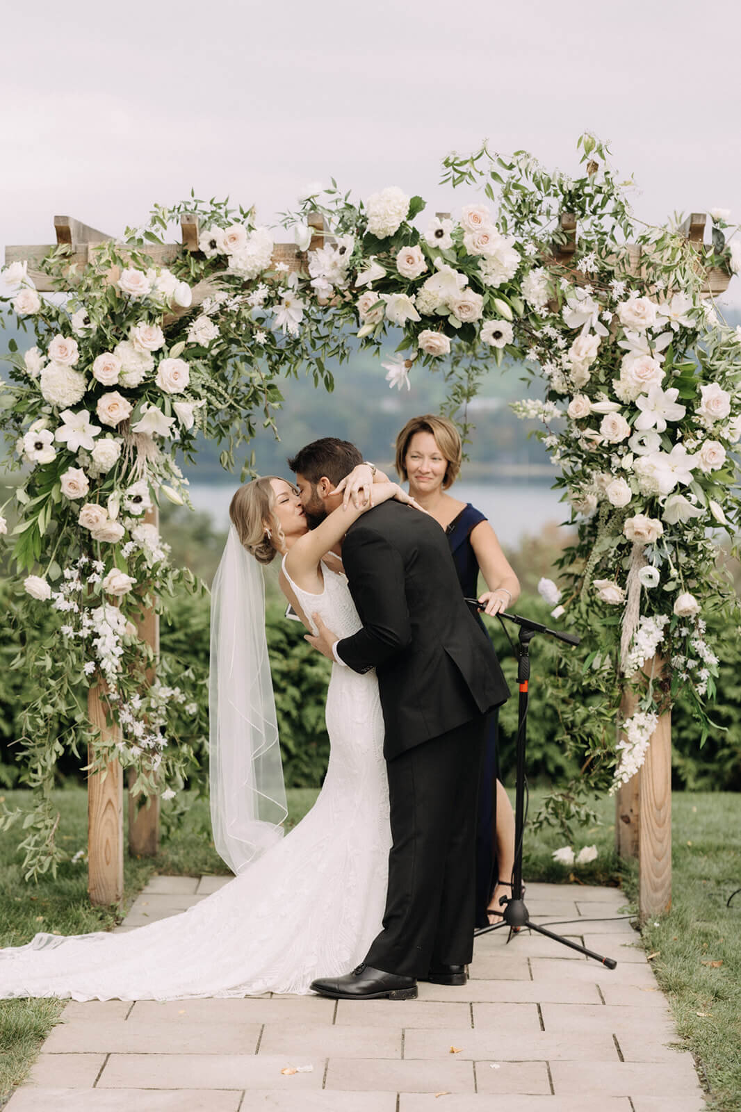 Bride and groom kissing underneath floral arch at Finger Lakes Wedding, New York
