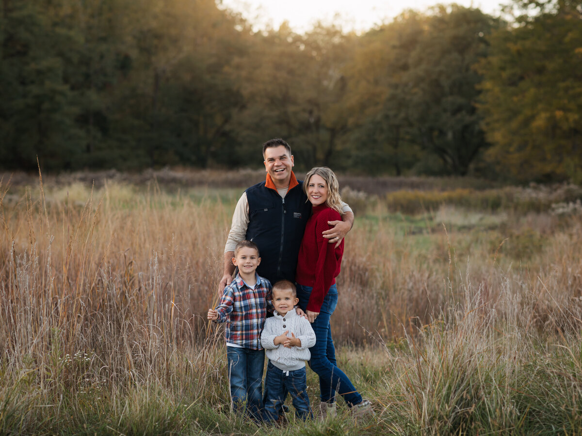 mom dad and two sons posed in field for family photoshoot cleveland family photography