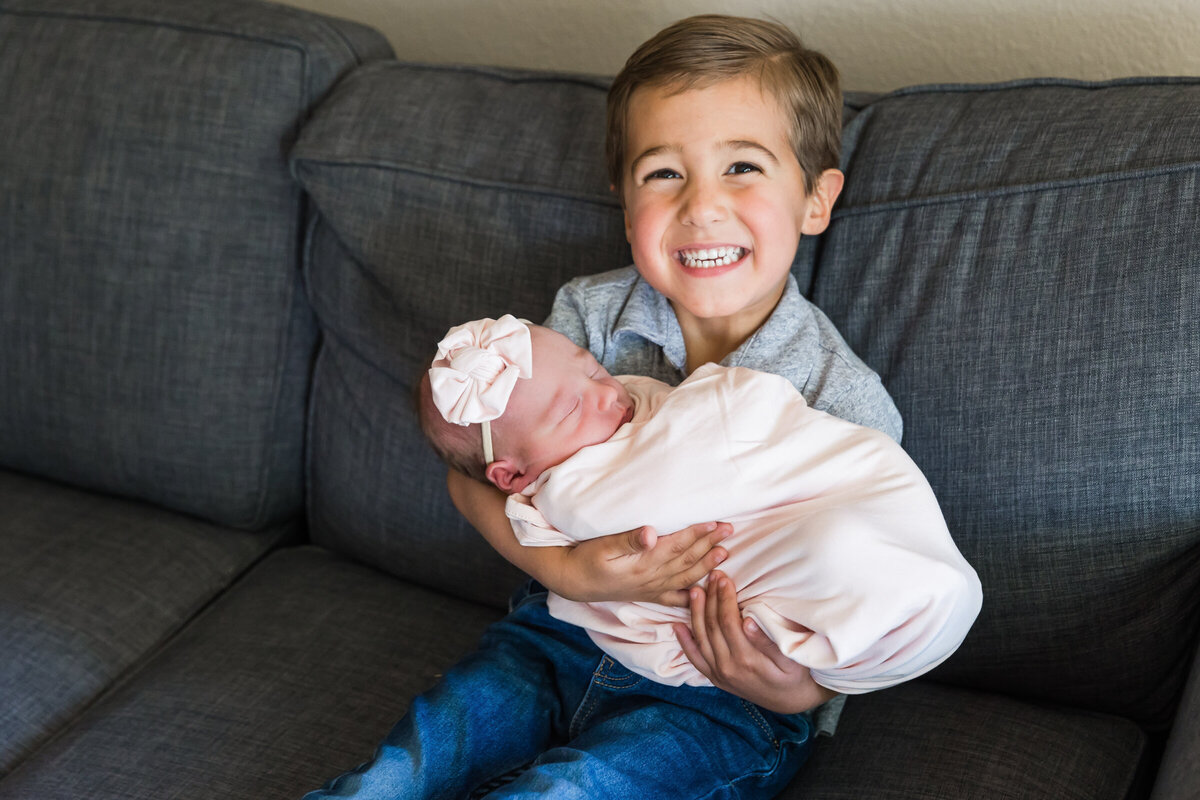 big brother holding newborn baby sister