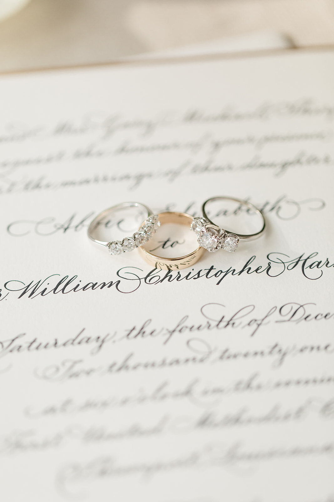 Wedding rings laying on wedding invitation