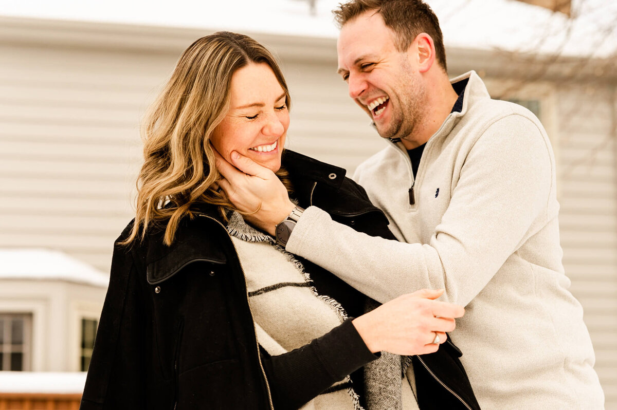 Couple laughing and playing in the snow during couples session with Everything is Grace Photography.