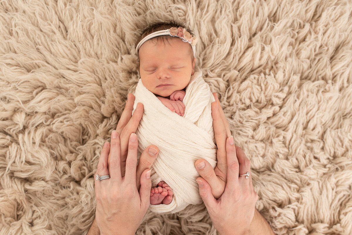 Picture of parents' hands on baby girl at indoor studio session |Sharon Leger Photography || Canton, CT || Family & Newborn Photographer