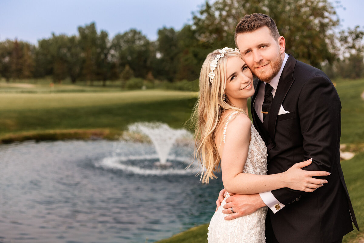 Bride and groom posing towards camera with a fountain in the background