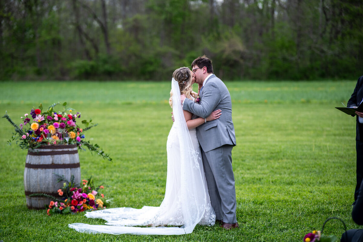 Bride and groom kissing at an outdoor ceremony with floral decor