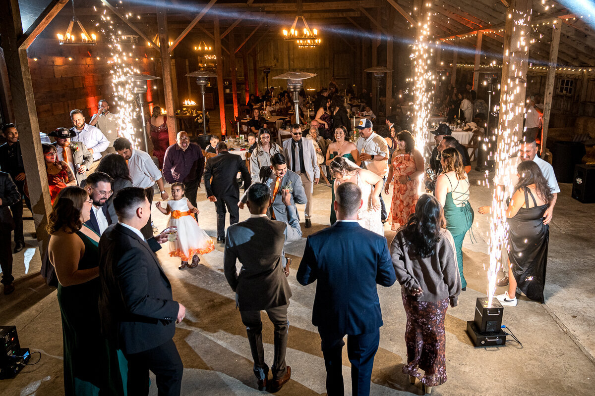 Guests surround the bride and groom while sparks glow as they enjoy an unforgettable moment of open dancing at The Barn by Fernbridge in Ferndale. A magical blend of joy, light, and love fills the air.