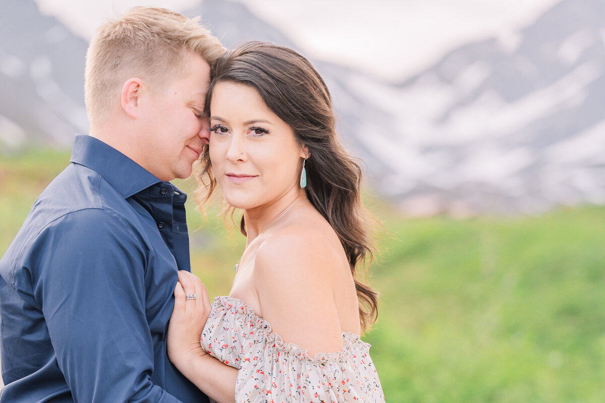 A bride to be getting kisses on her temple during their engagement session under the Alaskan midnight sun by JoLynn Photography, a destination wedding photographer