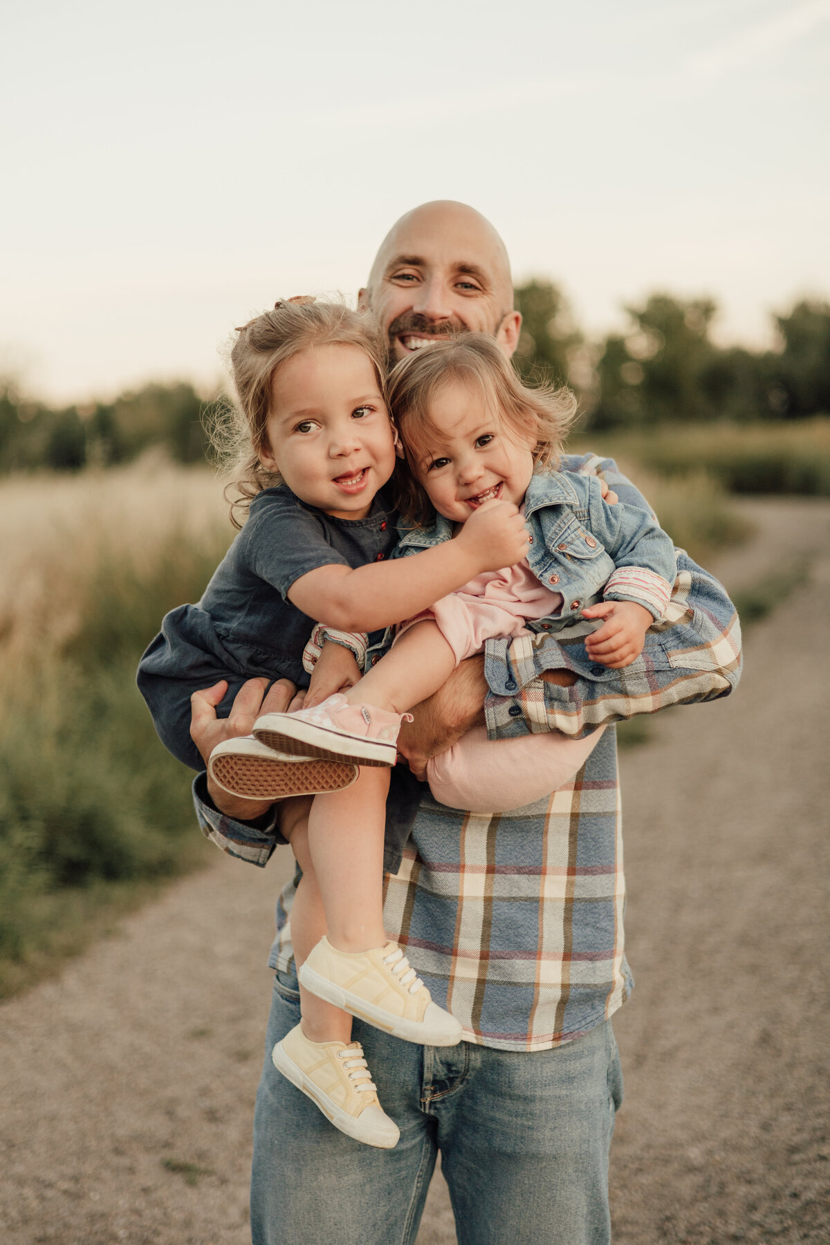 dad holding two daughters all smiling during lifestyle family session with alexis adkins photography in longmont colorado