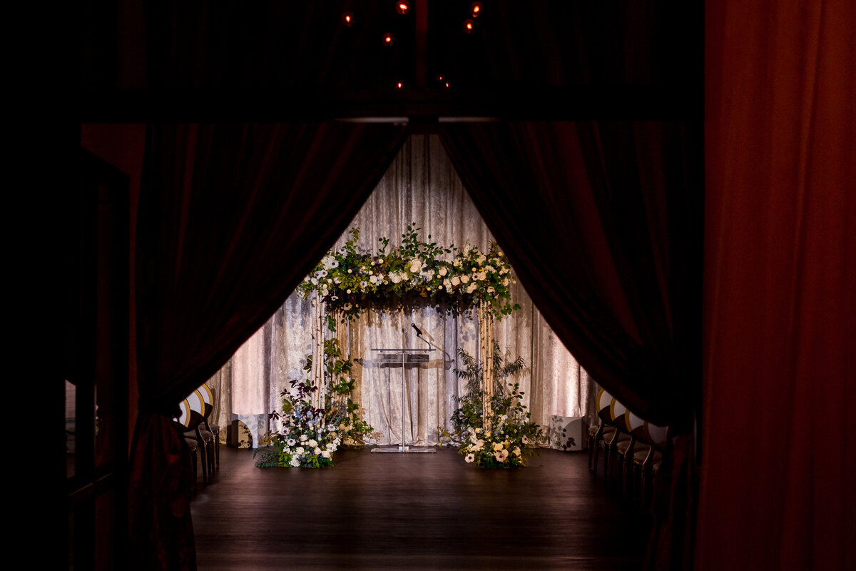 An intimate woodsy arch of flowers decorates a stage for a wedding ceremony at the Atwater Club.