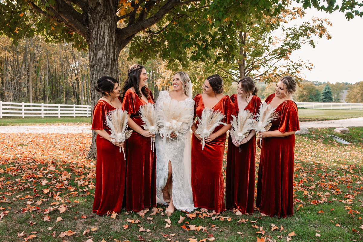 bride laughs with bridemaids in velvet dresses at fall wedding
