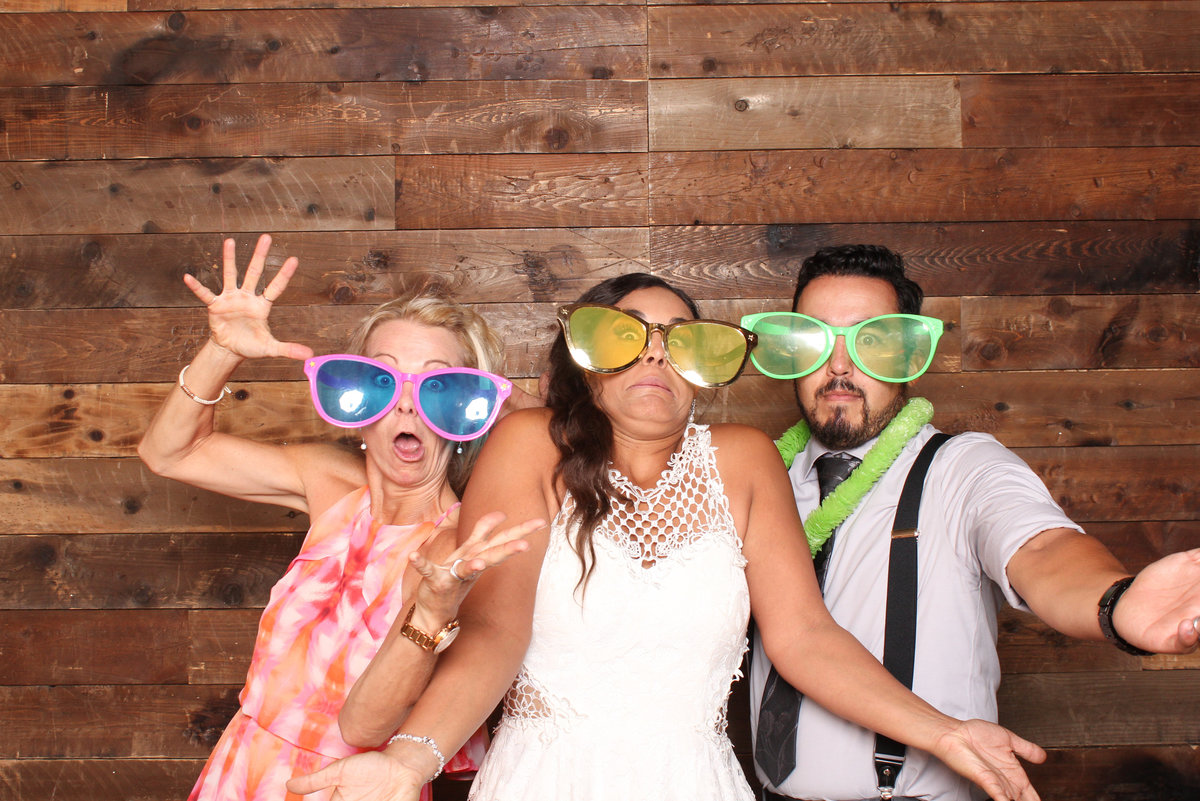 Bride pose with friends all wearing big glasses in a photo booth rental