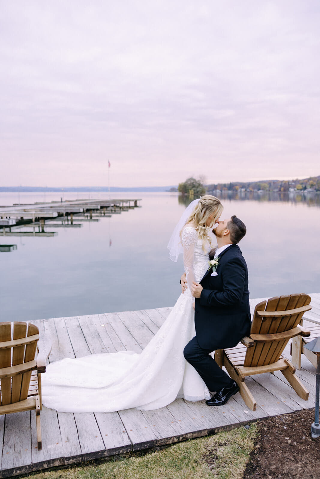 Groom sat down on deckchair looking up at bride at The Lake House on Canandaigua