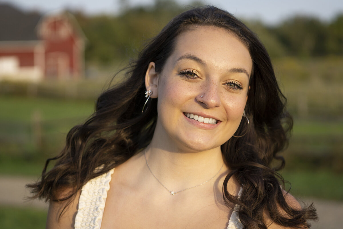 Senior photo of a young woman in front of a barn