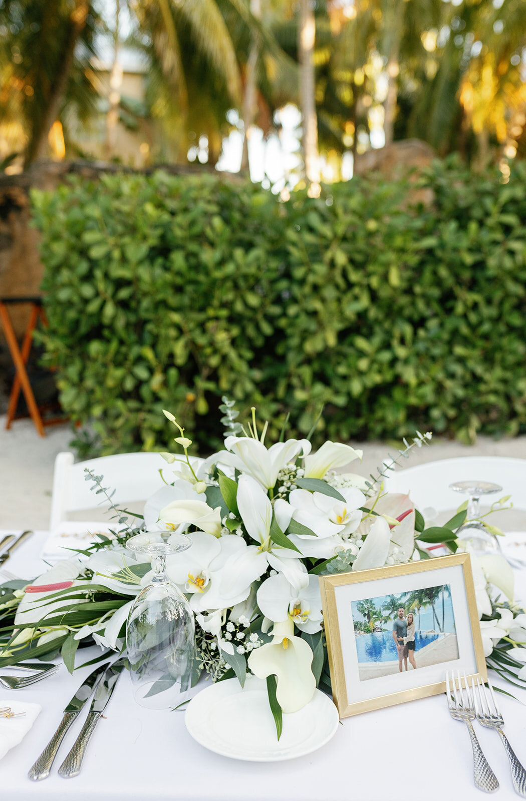 A beautifully styled reception table featuring fresh white florals, tropical greenery, and golden accents at Casitas at Cheeca.