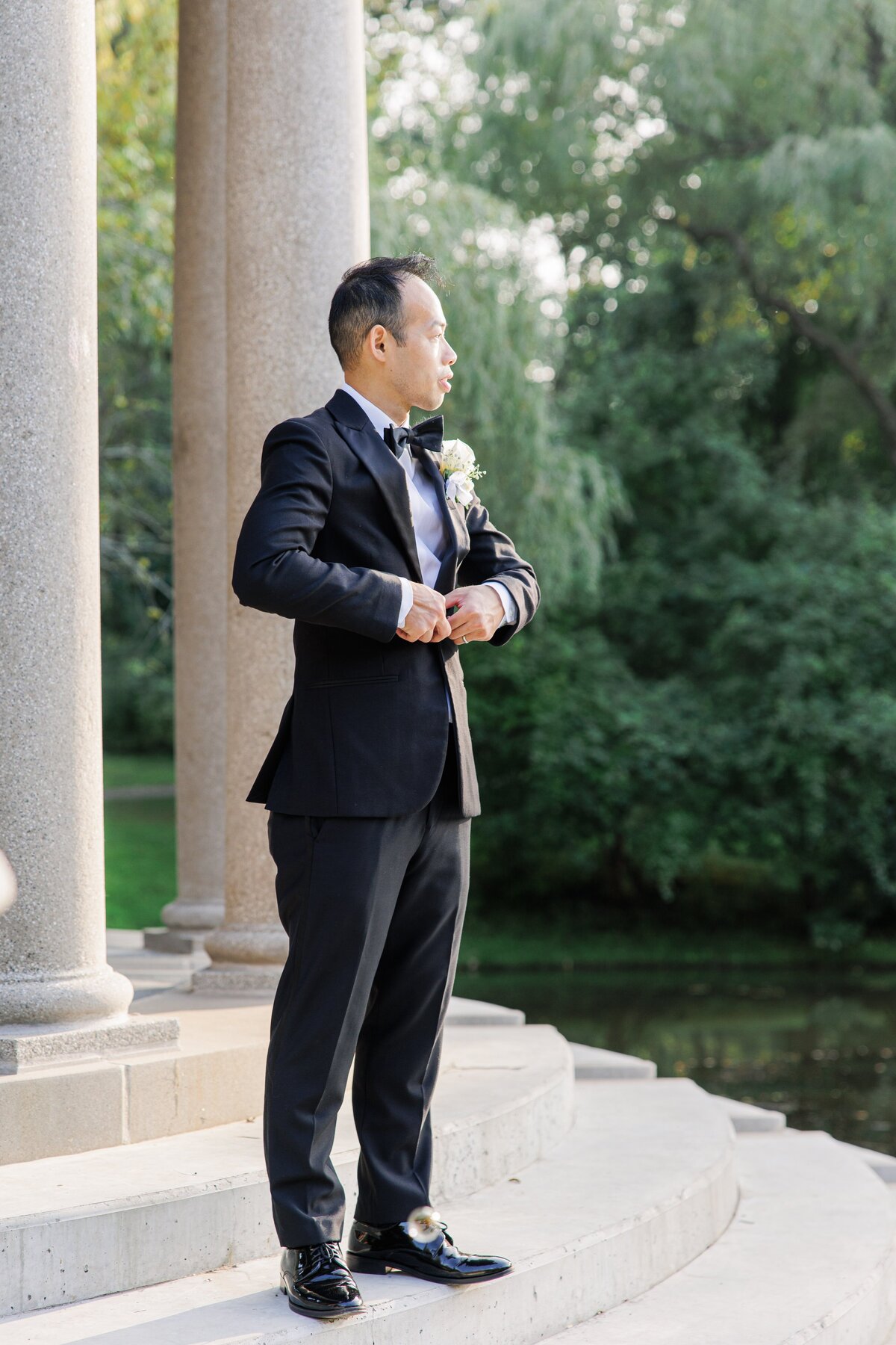 Groom buttoning his suit jacket for Boston wedding pictures