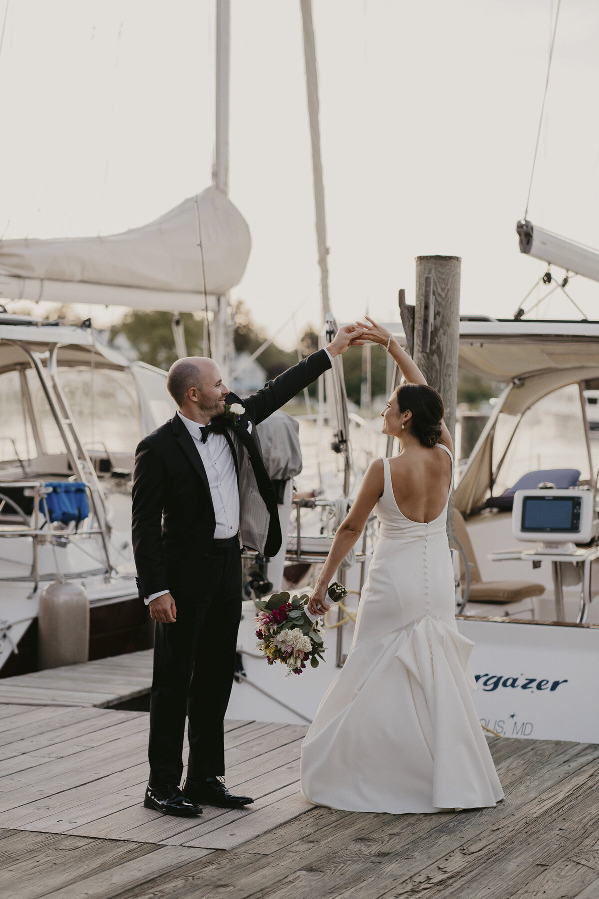 Groom twirling bride on a dock in Maryland near the water