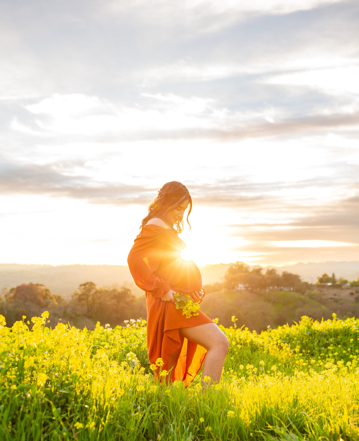 woman embracing pregnant belly in a field