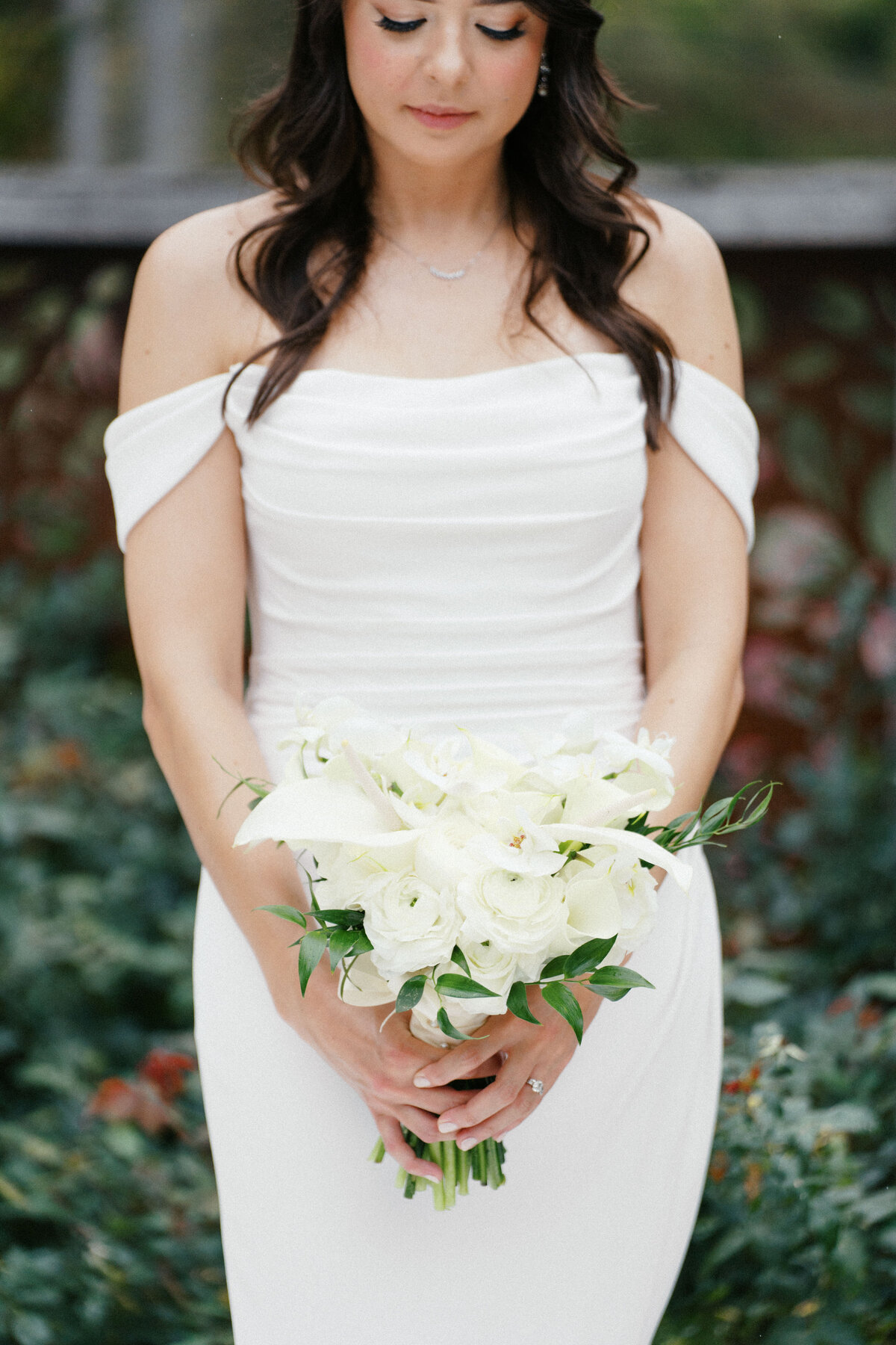 Bride in off-the-shoulder gown holding white bouquet at Sapphire Creek Winery