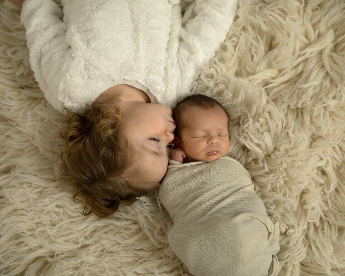 Big sister laying next to her newborn brother.