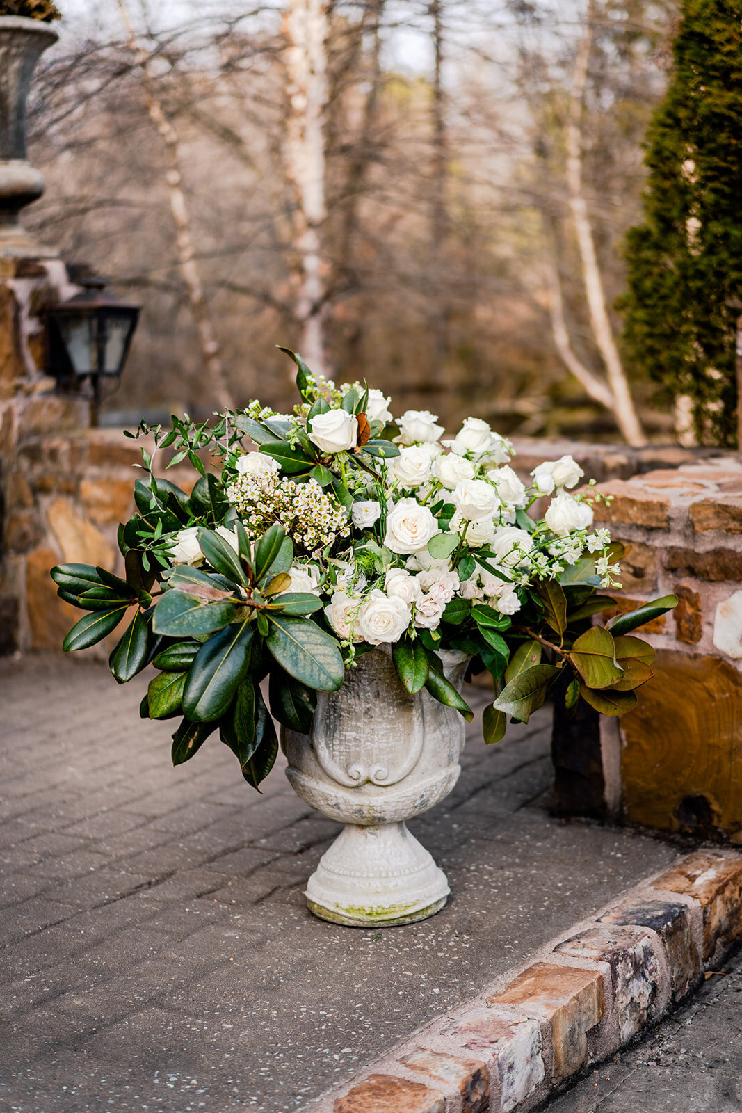 green and white wedding floral arrangement in stone urn
