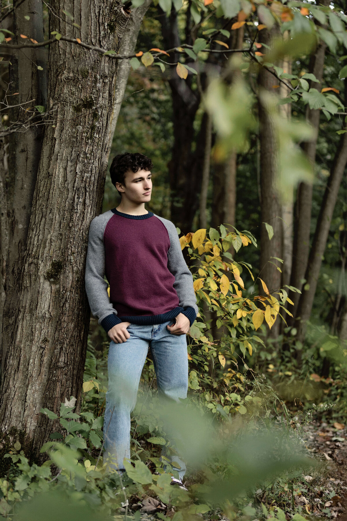 Senior photo of a guy leaning again a tree at Asbury Woods in Erie Pa