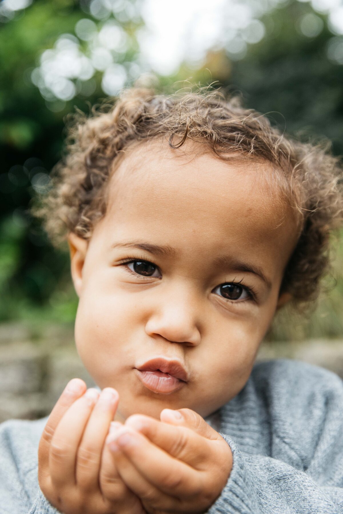 Toddler girl is sweetly blowing kisses at the camera.