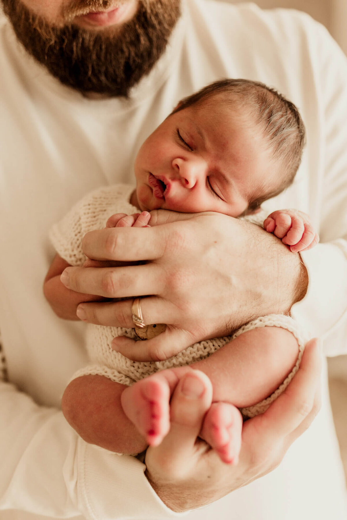 Father holds his son in his arms as his baby sleeps.