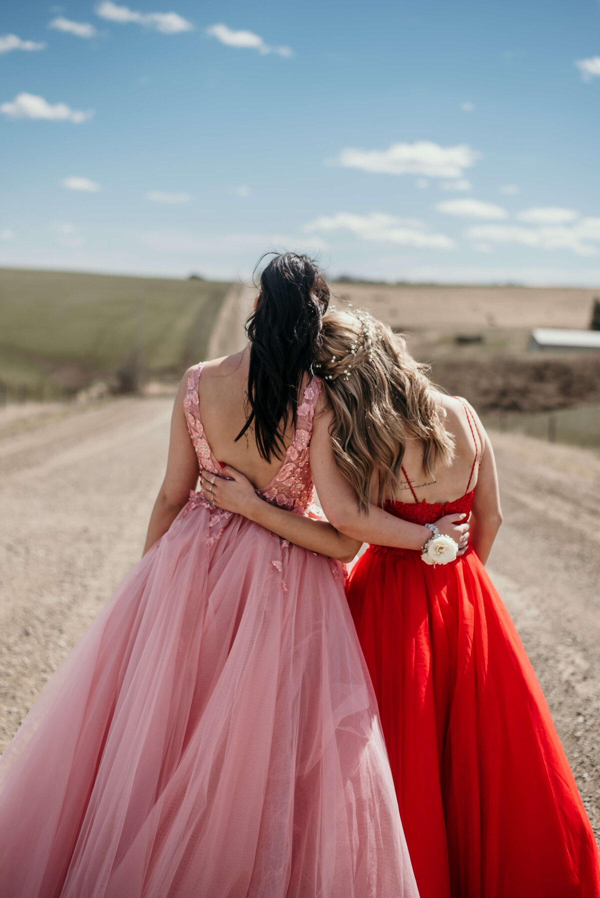 backs of two teenagers on their graduation day in dresses