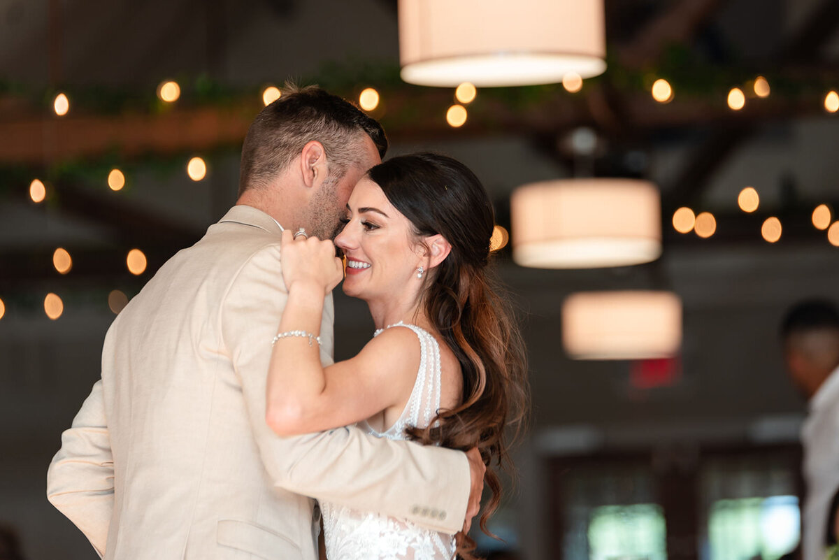 The bride and groom share a close dance, surrounded by soft lighting and greenery