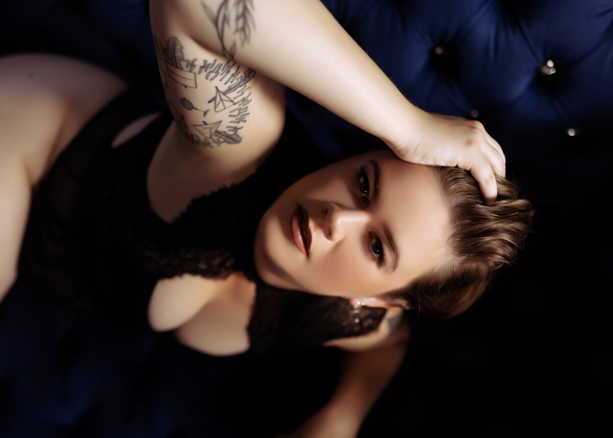 close up boudoir photo of woman with ink and short hair on blue couch elkridge