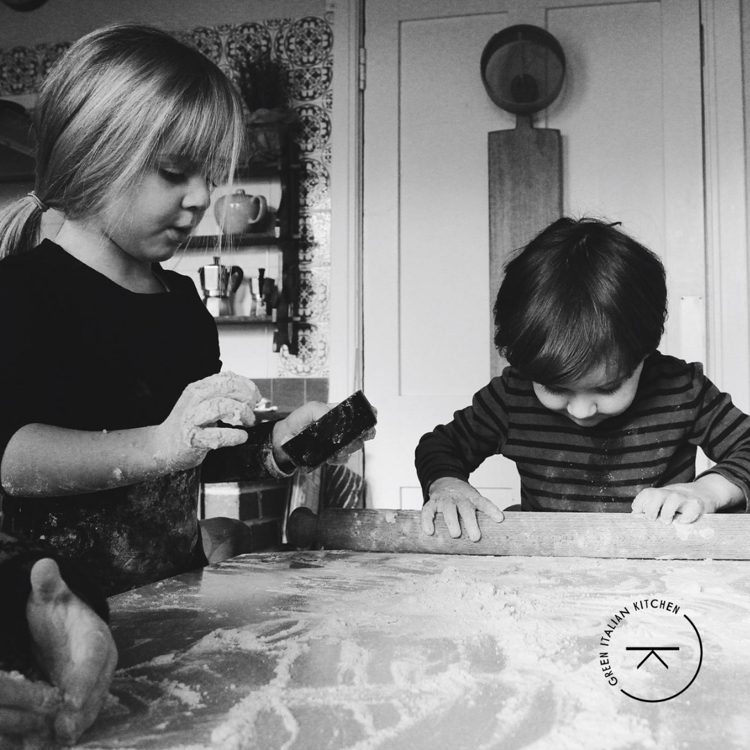 GITK custom circular logo design with table icon in the centre overlsi on black and white image of children baking.