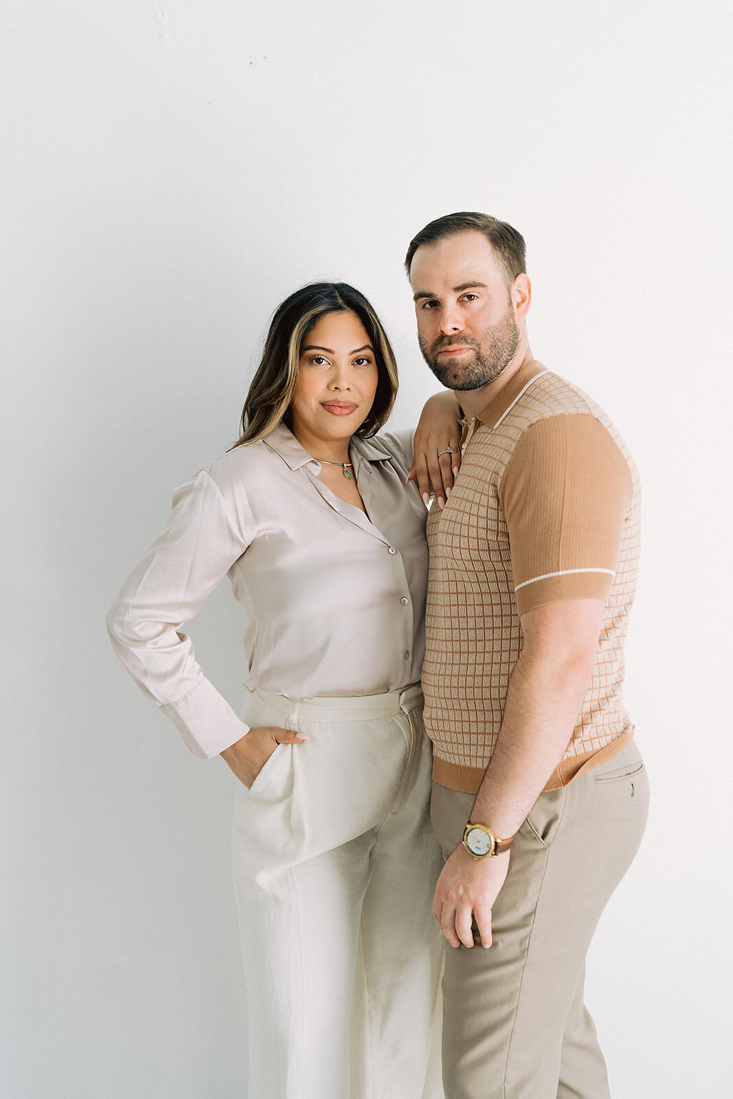 Engagement photo of a stylish couple posing together against a white wall at the Lumen Room in Austin