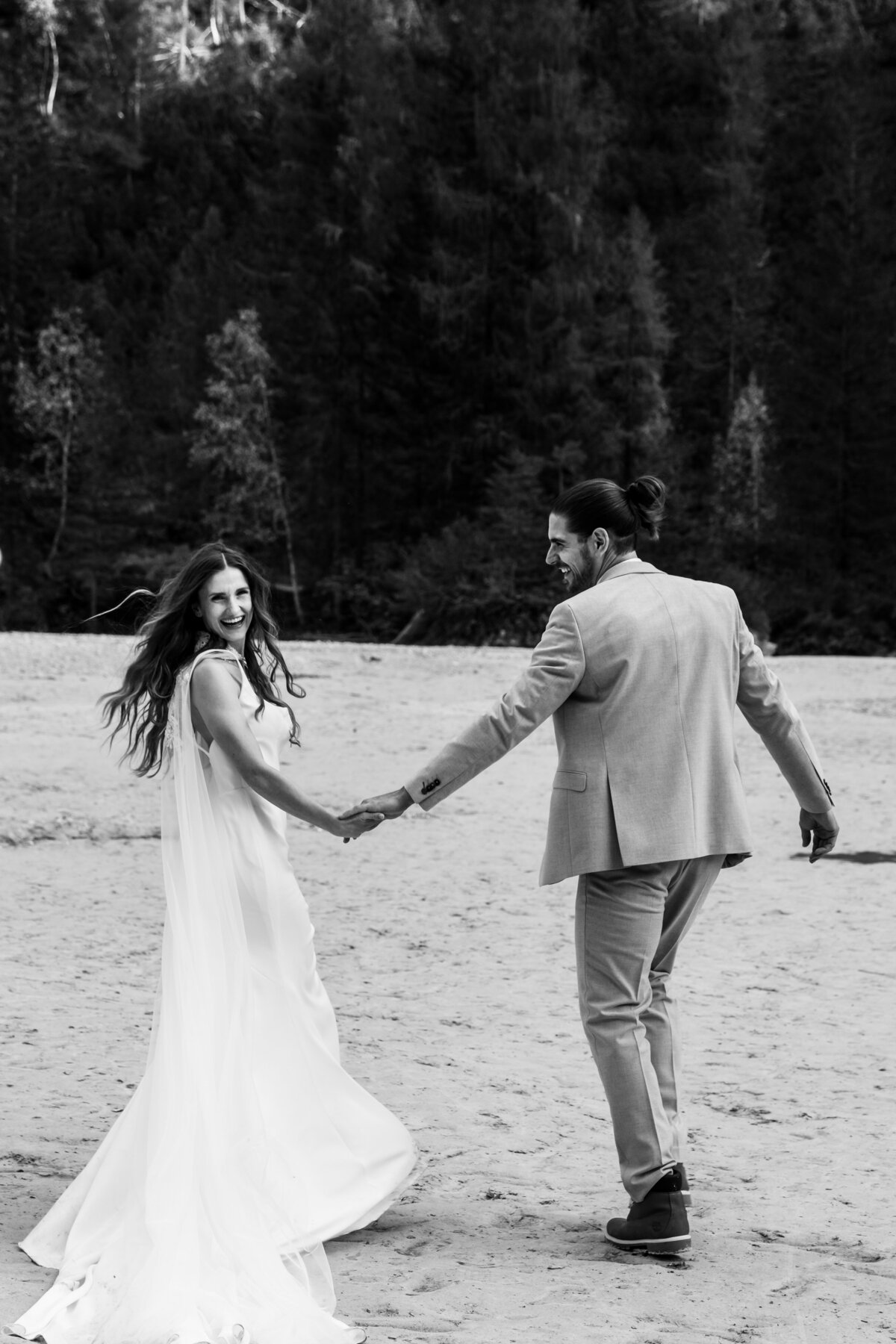 Candid elopement photo of the couple laughing by a crystal-clear lake.
