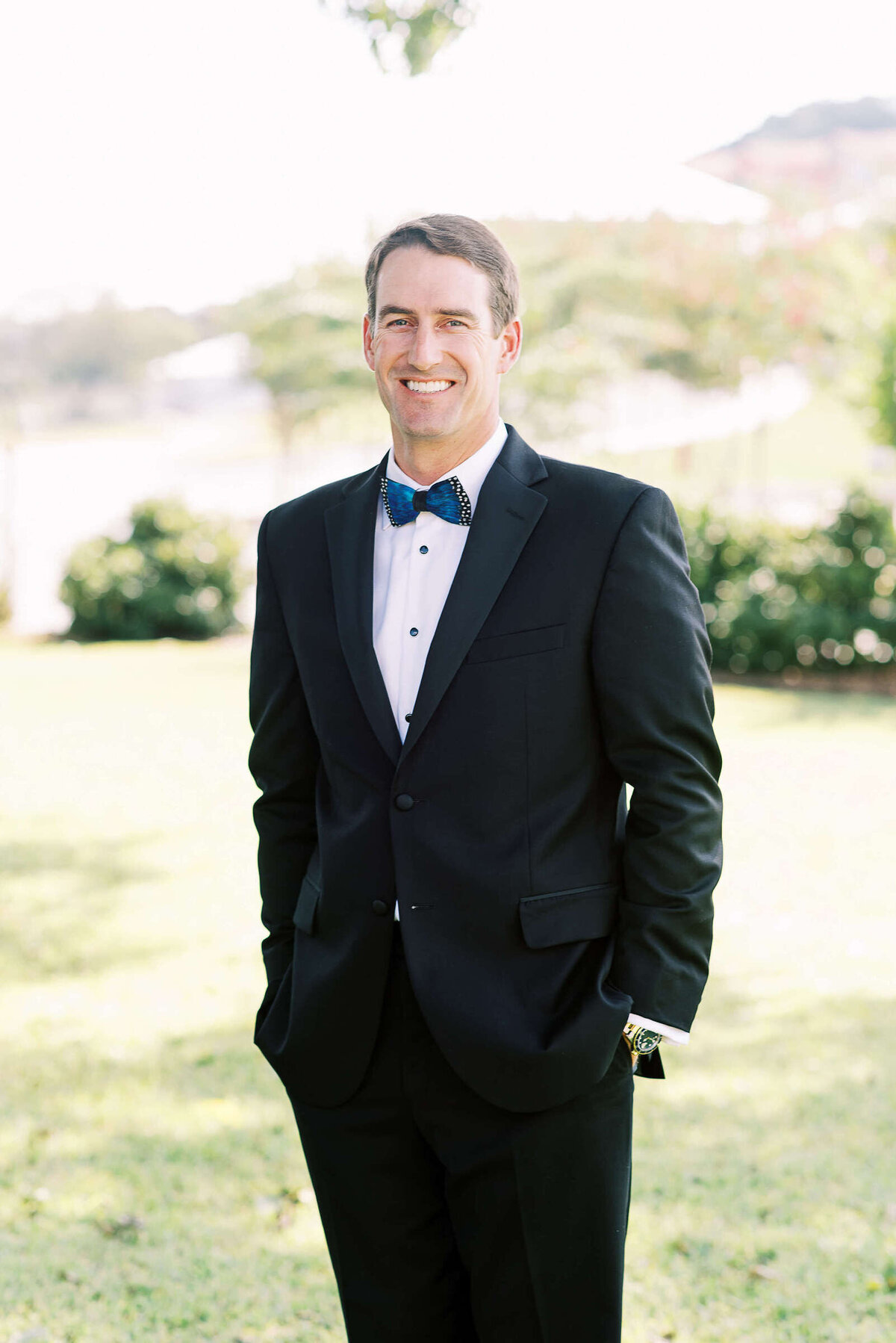 Classy groom smiles at the camera in the Texas hill country