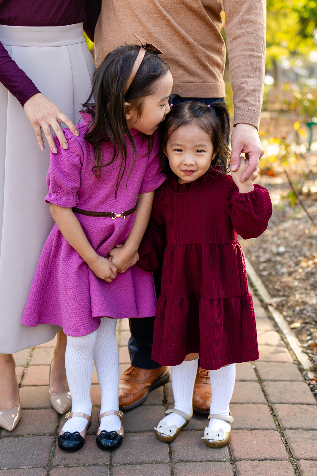 Sisters holding hands and smiling during a Burlingame garden family photoshoot – Ellobelle Photography