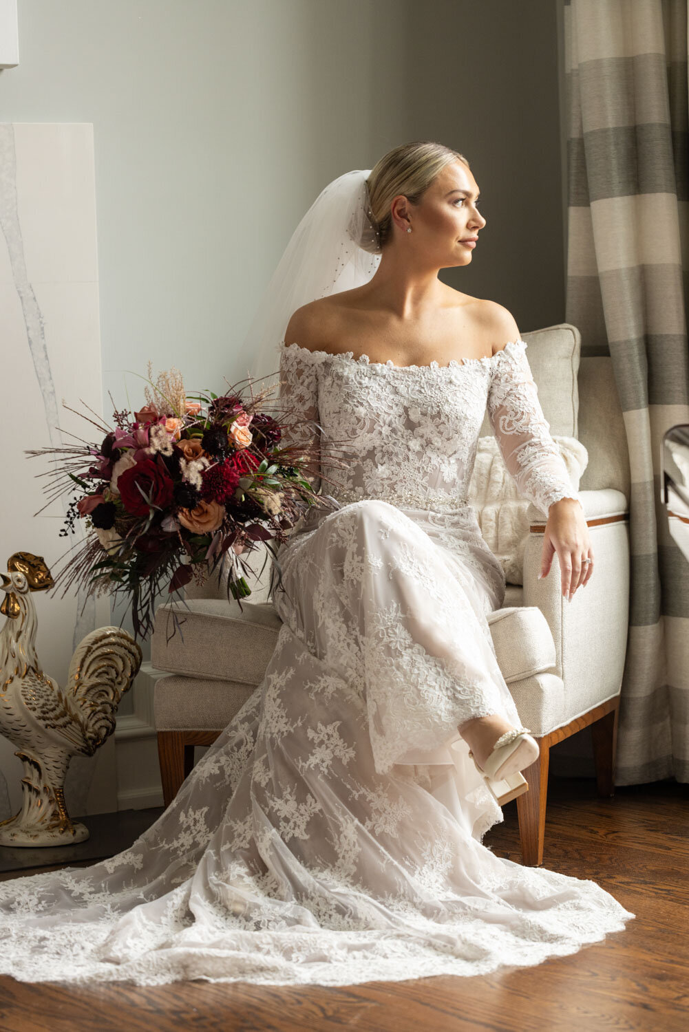 A woman in a wedding dress is sitting in a chair with a bouquet of flowers.
