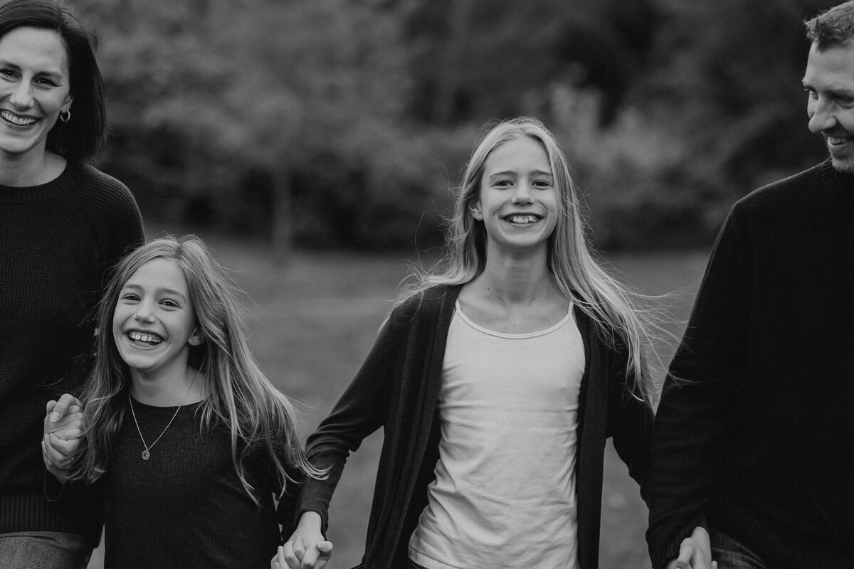 Family running towards the camera on Mercer Island, WA, laughing and enjoying a playful moment together.